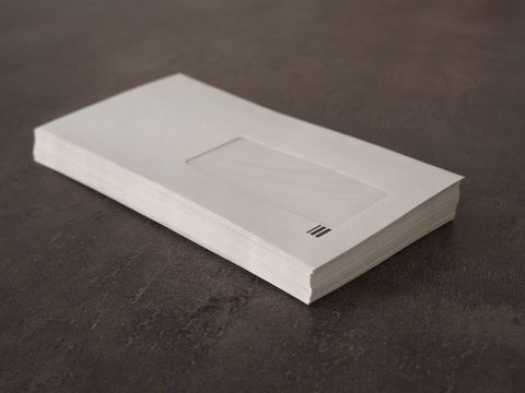Stapel weißer Fensterbriefumschläge auf einer dunklen Steinoberfläche