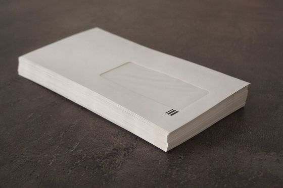 Stack of white window envelopes on a dark stone surface