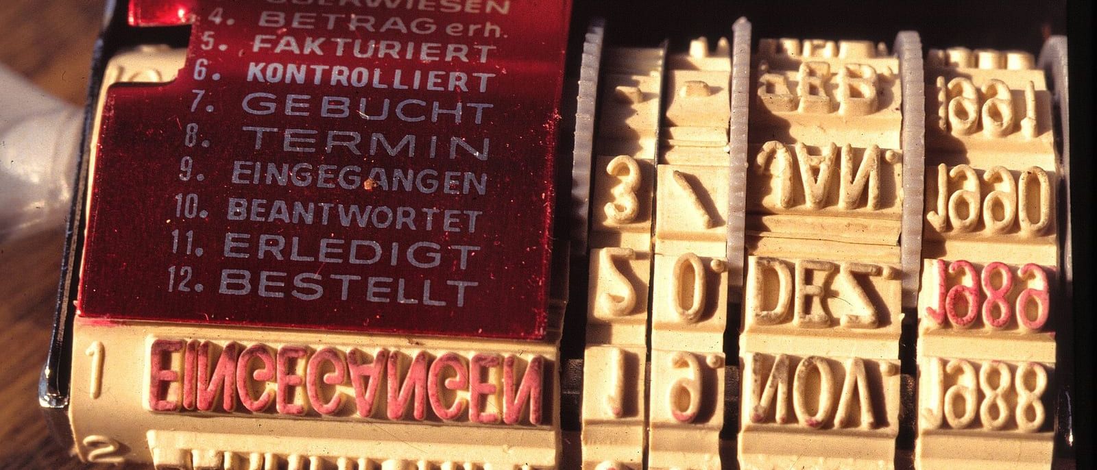 Alter Buchungsstempel mit Datumsrädern und Feldern wie Fakturiert, Gebucht und Bezahlt