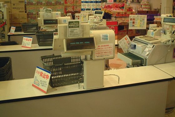 Closed supermarket checkouts with shopping baskets and customer displays