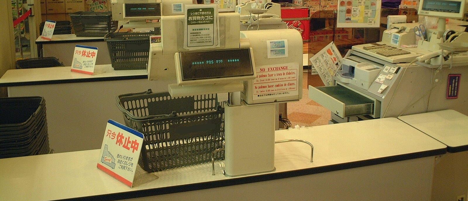 Geschlossene Kassen mit Einkaufskörben und Displays im Kassenbereich eines Supermarkts