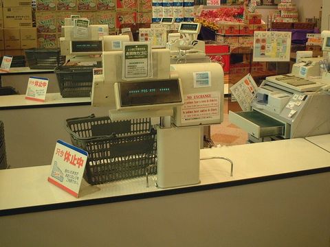 Geschlossene Kassen mit Einkaufskörben und Displays im Kassenbereich eines Supermarkts