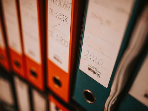 Aktenordner in Orange und Petrol im Regal, Rückenschild mit Jahreszahl 2020