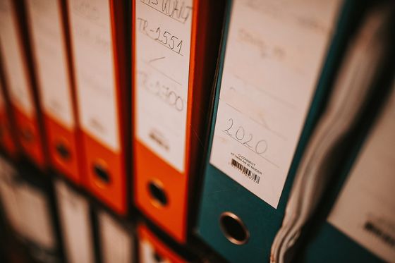 Aktenordner in Orange und Petrol im Regal, Rückenschild mit Jahreszahl 2020